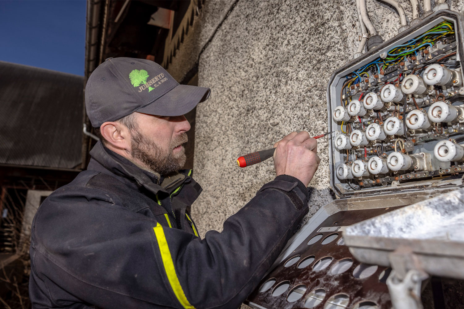 Elektriker kontrolliert einen alten Sicherungskasten mit Schraubsicherungen