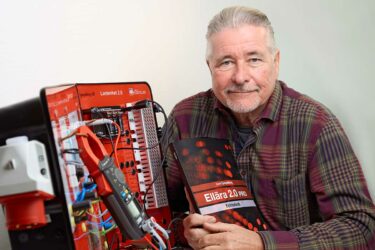 Läromedelsförfattaren Sven Spiegelberg som sitter vid ett bord där också hans labbutrustning står, den används som en modell av ett lågspänningsnät.