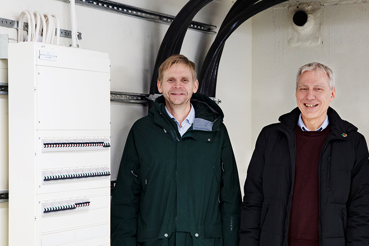 Jan Olin, Epspot, och Ulf Näslund, Vasakronan, bredvid elcentralen i garaget där även kommunikationen till och från laddboxarna samordnas. Foto: Stina Gullander
